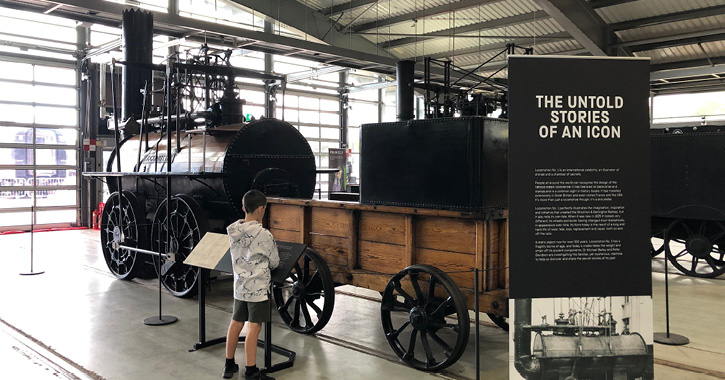 little boy looking at historic steam engine inside Locomotion museum